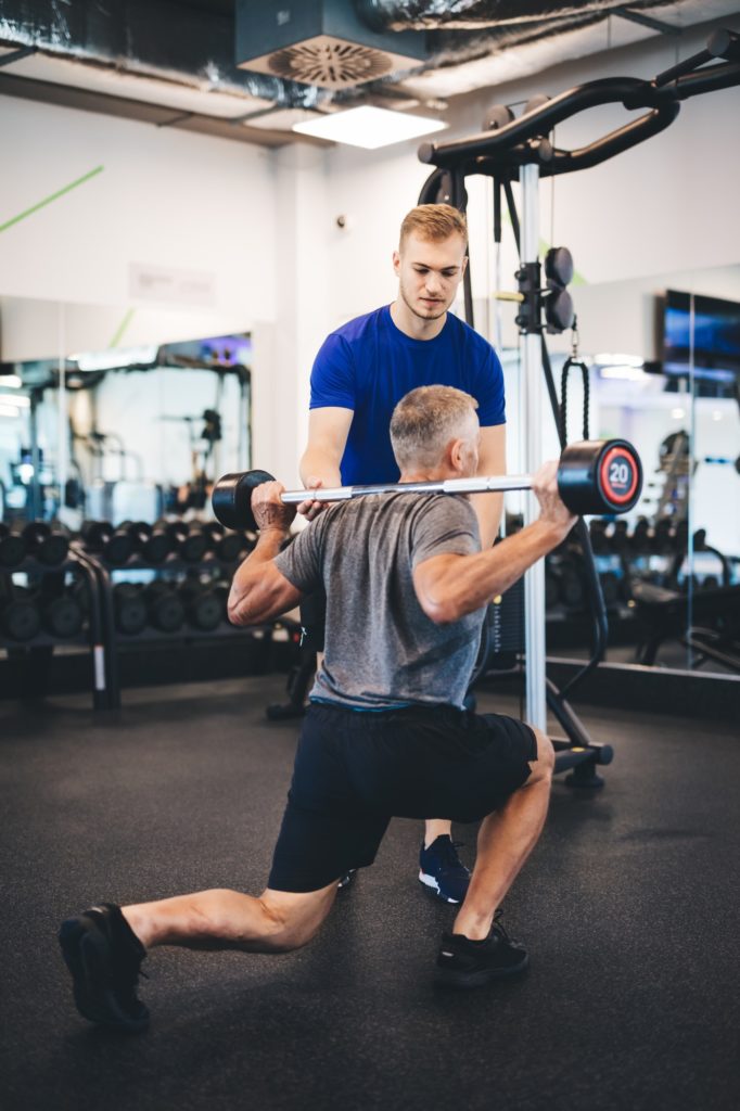 Senior man exercising with personal trainer.